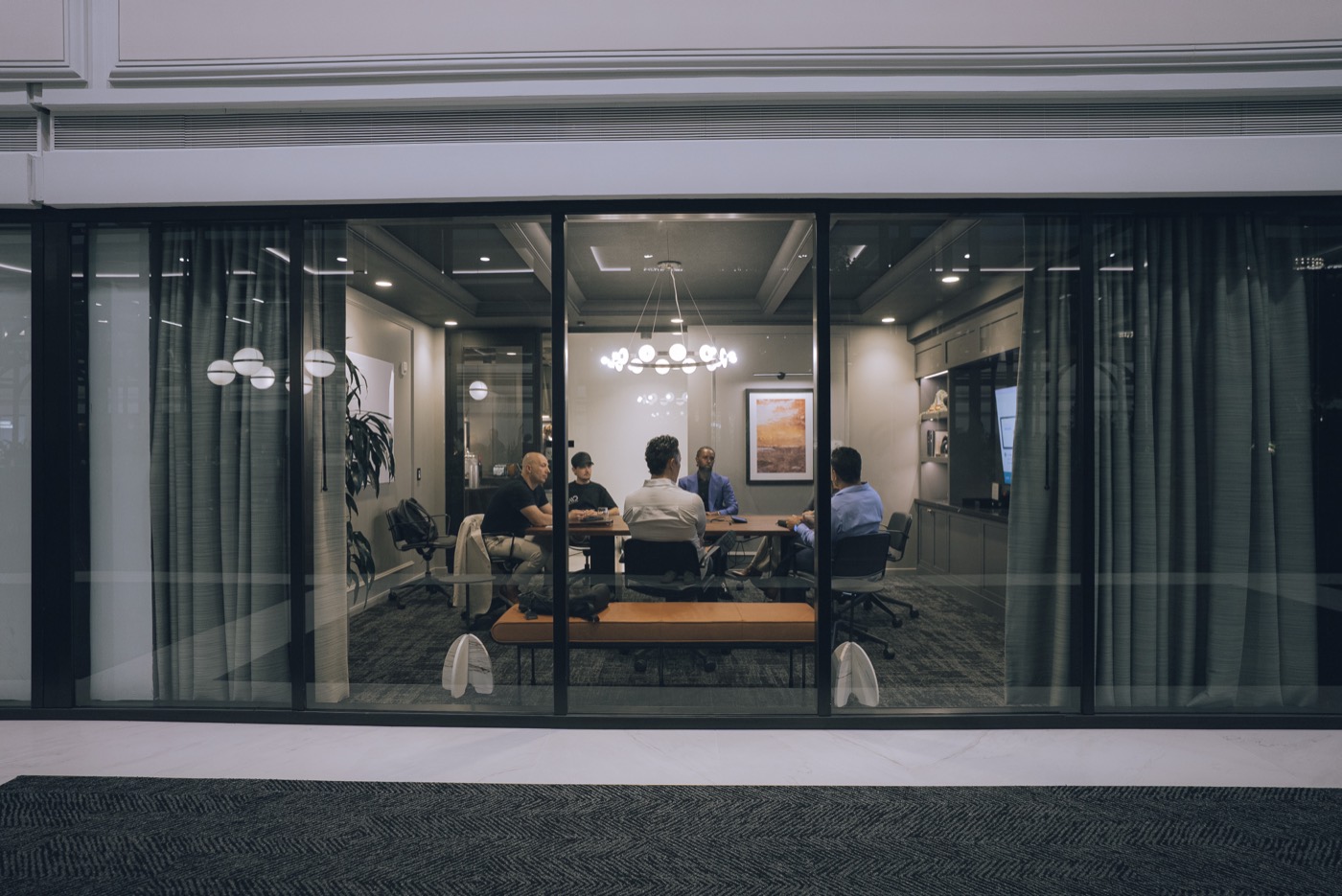 Members around the table in the meeting room, seen through the glass